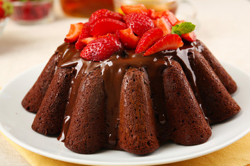 Tasty chocolate muffin with glaze and berries on table close up