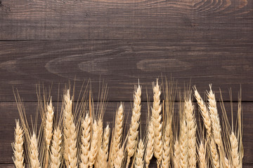 Wheat ears on the wooden background. Top view