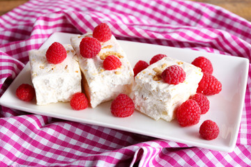 Sweet nougat with nuts and raspberries on plate close up