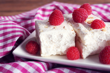 Sweet nougat with nuts and raspberries on plate close up