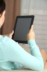 Female hand holding PC tablet on home interior background