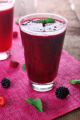 Berry cocktails and fresh berries on pink napkin on wooden background