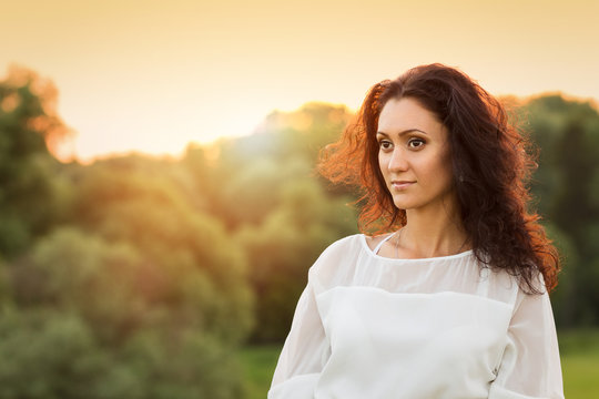 Young gorgeous lady in white dress in sunset beams