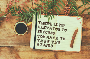 success and inspiration phrase. open notebook with text next to cup of coffee over wooden table....