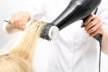 Kobieta u fryzjera, fryzjer modeluje włosy na okrągłej szczotce - obrazy, fototapety, plakaty