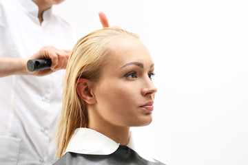 Rozczesywanie włosów. Kobieta na fotelu fryzjerskim podczas zabiegu stylizacji włosów