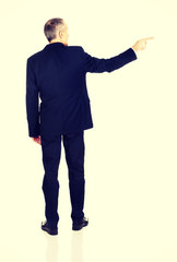 Full length back view businessman pointing right