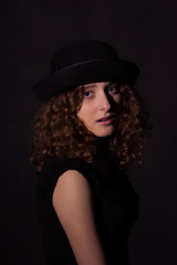 Fototapeta na wymiar Low key portrait of beautiful girl in black hat