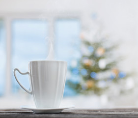 white cup on background Christmas fir and window