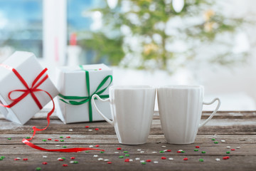 two cups with gifts on background Christmas tree