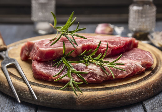 raw pork with rosemary on a wooden board with a fork, close up