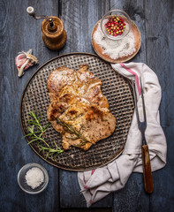 grilled meat with spices on an iron baking tray with a napkin and fork on a rustic wooden...
