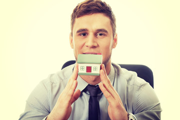 Businessman with house model by a desk.