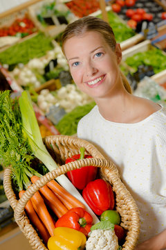 Woman holding colourful basket of vegetables