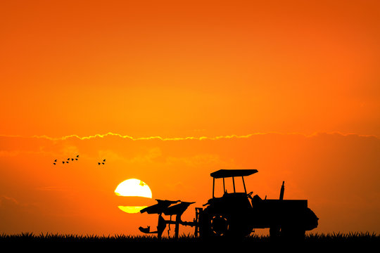 tractor in the fields at sunset