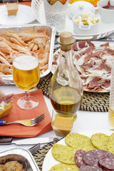 Jar of olive oil beside a beer glass and several exponents of Spanish gastronomy