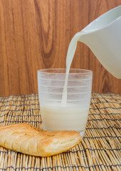 Milk from ceramic jug pouring into glass