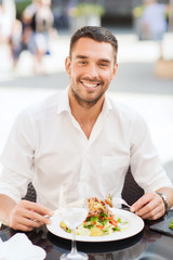 happy man eating salad for dinner at restaurant
