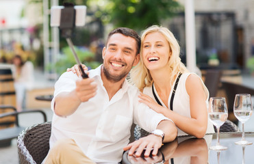 happy couple taking selfie with smartphone at cafe