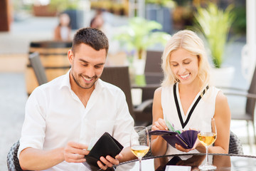 happy couple with wallet paying bill at restaurant