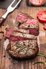 Medium rare roasted beef steak slices on rustic wooden background, close up
