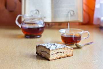 Still life composition: morning tea with sweet cake and reading book.Selective focus and blurred background