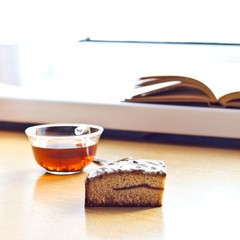 Still life composition: book tea cake. With selective focus and blurred background. Sunlight from window