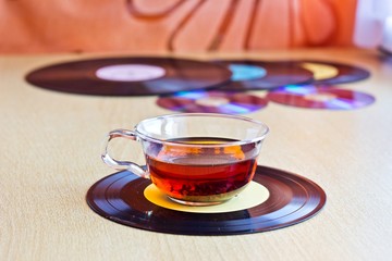 Strong black tea in glass cup on vinyl record discs. Selective focus on cup