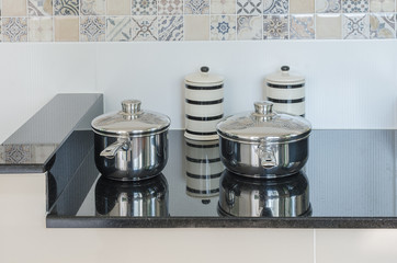 set of stainless pot on black granite counter in kitchen room