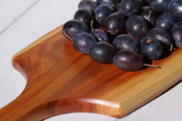 Damsons on wooden chopping board.
Damsons piled on a wooden chopping board.