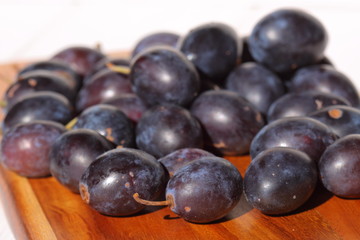 Damsons on wooden chopping board.
Damsons piled on a wooden chopping board.
