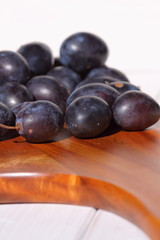 Damsons on wooden chopping board.
Damsons piled on a wooden chopping board.