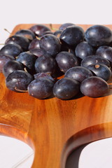 Damsons on wooden chopping board.
Damsons piled on a wooden chopping board.