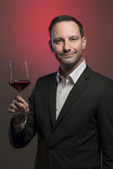 man tasting red wine in jacket in front of red background