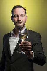 man tasting white wine in jacket in front of yellow background