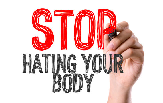 Hand with marker writing the word Stop Hating Your Body