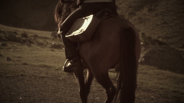 A cowboy riding his horse in the mountains on sunrise Sepia in