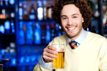 Smiling young man holding a glass of beer
