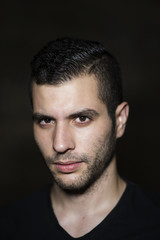 Obraz premium Young 20s modern man posing on dirty wall with ambient ligh.