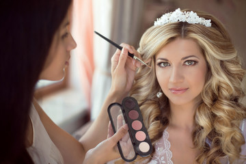 Professional Stylist makes makeup bride on the wedding day. 