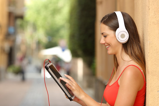 Girl browsing a tablet and listening with headphones