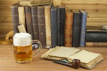 Foto auf Acrylglas Kühles Glas Bier auf dem Tisch. Entspannen Sie sich bei einem guten Buch und einem kühlen Glas Bier. Das Konzept entspannen bei einem guten Bier. Ein Glas Bier für die Leser des Buches einschenken. Alkohol und Studium. © martinfredy