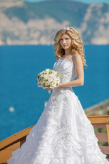 Fototapeta na wymiar Beautiful blond bride in wedding dress with bouquet of flowers o