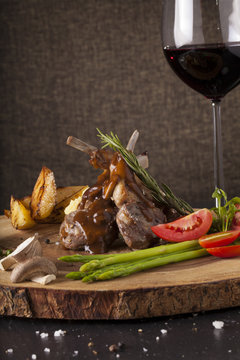 Rack of lamb steak, Rack of lamb steak cut in pieces decorate and seasoning with vegetable and herbs and red wine serve on chopping wood block