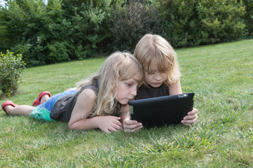 Fototapeta na wymiar Two blond boys are looking to the tablet