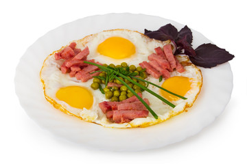 Fried eggs with sausage, onion and green peas on a white plate. Isolated on white.