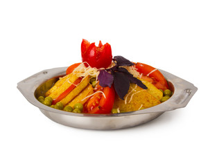 Meat baked with slices of potatoes, tomatoes, green peas and cheese. On a plate isolated on white.