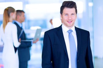 Fototapeta premium Portrait of young businessman in office with colleagues in the