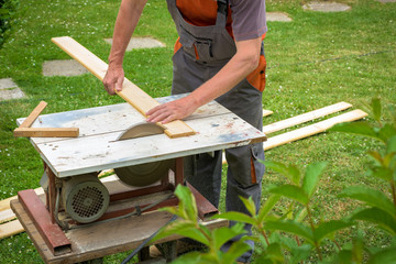 Carpenter working with electric buzz saw cutting wooden boards