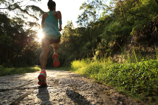Runner athlete running on forest trail. woman fitness jogging workout wellness concept.